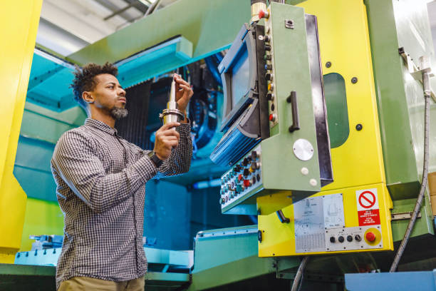 istock Serious Adult Mixed Male Electrical Engineer Fixing A CNC Machine In A Production Unit 1960127614