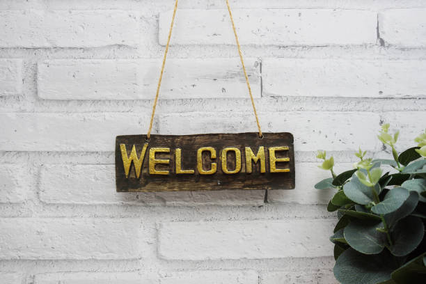 istock Welcome sign hanging with rope on white brick wall background 1960137068