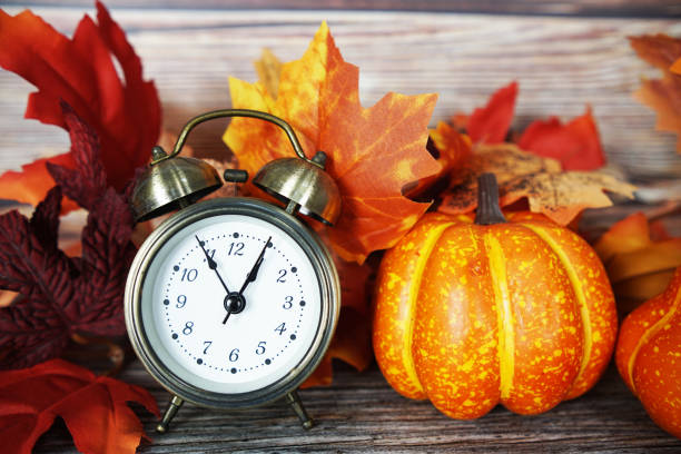 istock Alarm clock with pumpkin and maple leaf on wooden background 1960139816