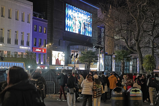 Central London, England, United Kingdom, Great Britain – 24th January 2024: In this photograph, a group of people can be seen walking along a London street.Leicester Square, Central London, England, United Kingdom, Great Britain – January 2024: In this photograph, Odeon Luxe Cinema which is the UK’s largest cinema chain and a large group of people can be seen walking along a London street in the iconic Leicester Square. Argylle's movie (Director: Matthew Vaughn) film poster (the movie features actors Henry Cavill, Bryce Dallas Howard, and Sam Rockwell) is seen on the facade of the cinema chain in Leicester Square in London, the UK.