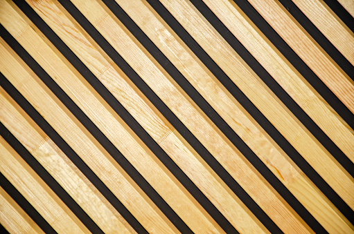 Wooden boards are arranged vertically and diagonally. The wall is lined with polished veneer. background, texture. lattice screen, partition or fence.