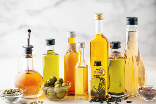 Various vegetable and seed oil in bottles on a bright background.