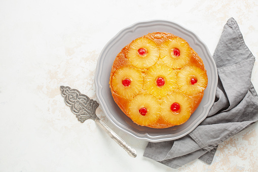 Homemade pineapple upside down pie with candied cherries . Tropical dessert on white background. Top view