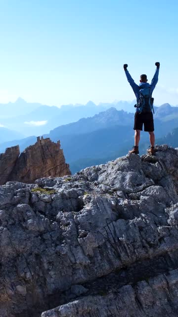 Hiker Raising His Arms on top of a Mountain in the Dolomite Alps