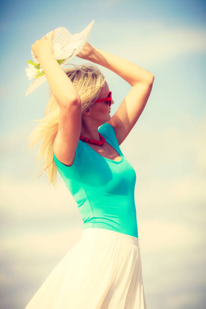 Summer time relax leisure concept. Attractive woman on the beach. Lady wearing sunglasses and hat