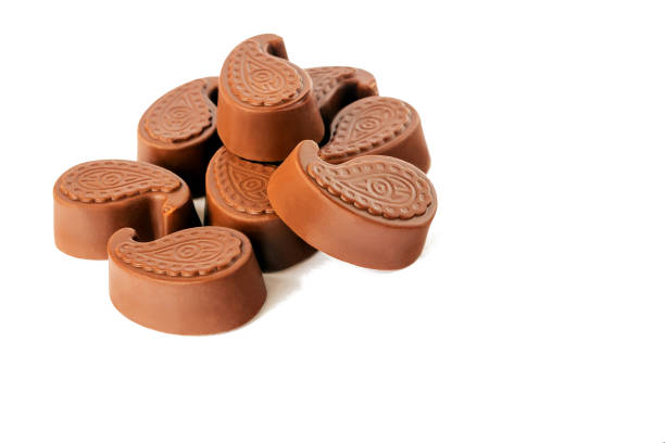 Milk chocolate candies lie on a white isolated background in a slide.