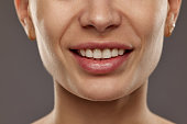 Cropped image of female face against studio background. Young woman smiling. Teeth whitening, dental care