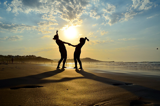 Mother and daughter, silhouette, figures, jump, laughter, joy, beach, sunset
