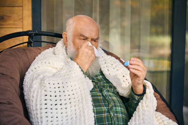 istock Sick old man is wrapped in fluffy blanket on veranda 1960239137