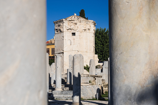 View of the iconic Tower of the Winds or Aerides, and several columns in the Roman Agora ( Athens, Greece) . It is landmark of Athens. Ancient Greek ruins in Athens city center at Plaka district. Concept of history and culture of old classical Athens.