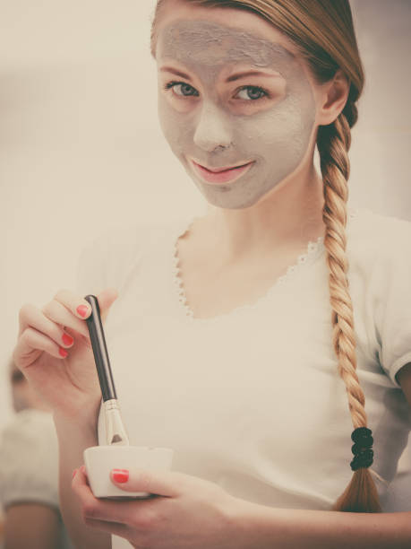 istock Woman applying with brush clay mud mask to her face 1960247690