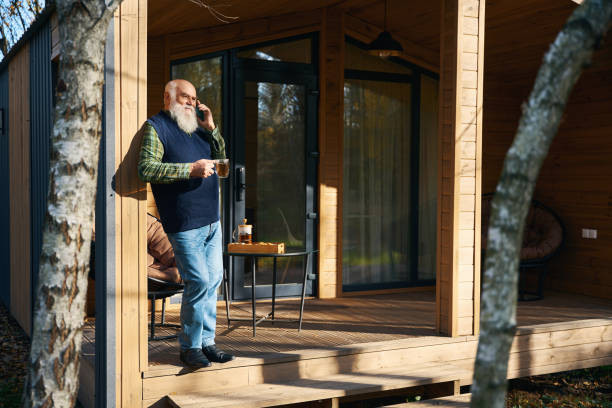 istock Gray-bearded old man communicates on a mobile phone on veranda 1960254571