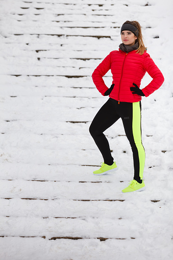 Outdoor sport exercises, sporty outfit ideas. Woman wearing warm sportswear running jogging outside during winter.