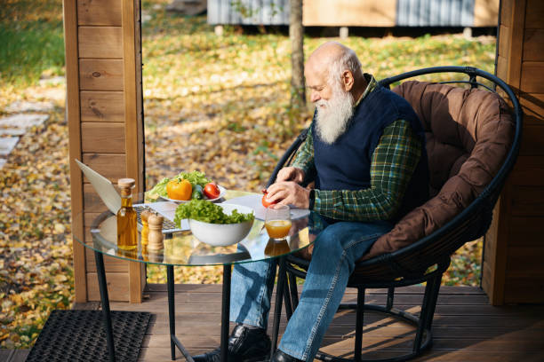 istock Pensioner sits on the veranda with breakfast and a laptop 1960273536