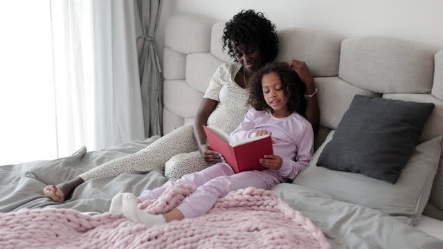 Mother and daughter reading together in bed