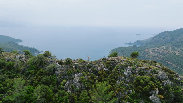 Man standing on beautiful seascape, Young man enjoying view from mountain top, man watching view from high and feeling free, freedom stance in nature