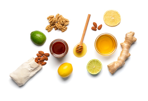 Conceptual composition of honey in a jars, dipper, walnuts, almonds, lemon, lime and ginger on a white background top view. ?itrus fruits and honey. The concept of organic products.
