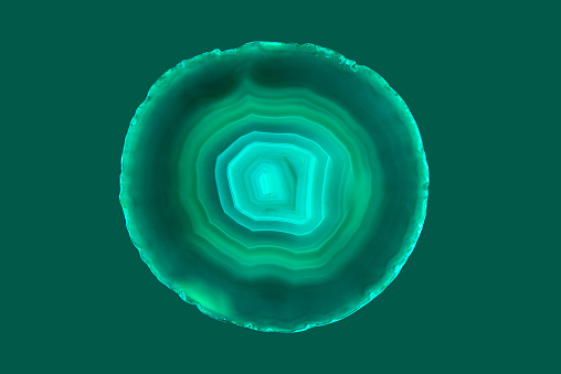 Close-up shooting of a green agate stone mineral surface isolated on white background. Its a macro shot shows nature beautiful details with back lit. Agate is a kind of natural gemstone. Abstract pattern. Good for Wallpaper texture background. Turquoise, green\n\n.