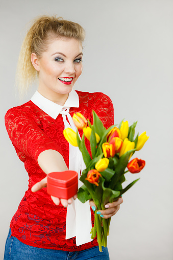 Woman holding bouquet of tulips flower and gift box in heart shape. Womans day, 8 march present.