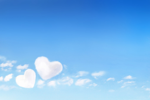 Fluffy clouds forming a hearts shape on blue sky background, soft focus. Heavenly clouds. Holidays of love, Valentine day, Mother day, romantic. Copy space. Empty place for message.