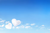 Clouds forming a hearts shape on blue sky background, soft focus.