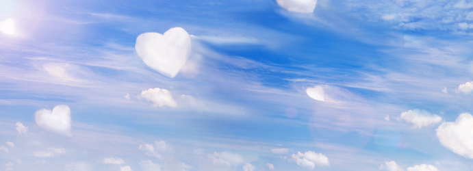 Fluffy clouds forming a hearts shape on blue sky background, soft focus. Heavenly clouds. Holidays of love, Valentine day, Mother day, romantic. Copy space. Empty place for message.