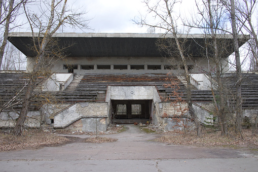 An abandoned football stadium in Pripyat. Overgrown with trees ruins of the stadium.
