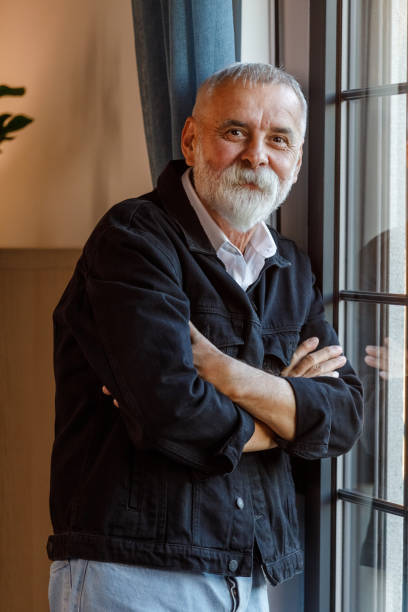 istock Charming mature man standing by the window, smiling at camera 1960336159