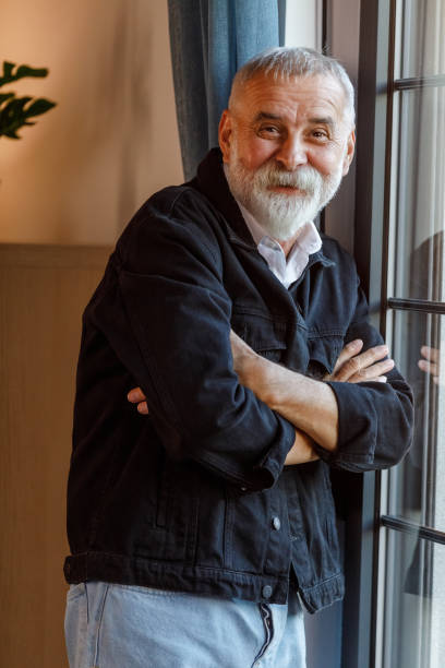 istock Charming mature man standing by the window, smiling at camera 1960336161