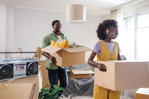 Photo of an extremely happy couple moving into their new house after saving money for a long time to buy it. Their dream came true!