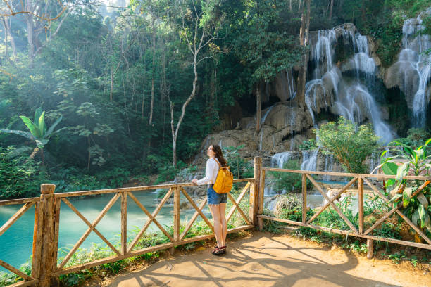 istock Woman enjoys refreshing  waterfall in tropical forest 1960372343