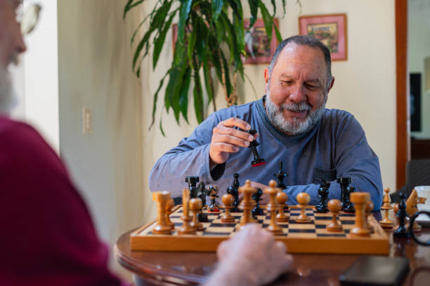 istock Latino men from the same nursing home where they live are together playing chess, distracting the mind. 1960373911