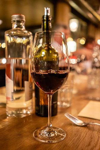 red wine is in wine glass on dinner table with bookeh effect vertical food and drink business still