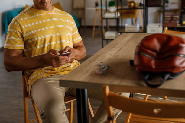 istock Man sitting at dining table, scrolling online via smart phone 1960398937