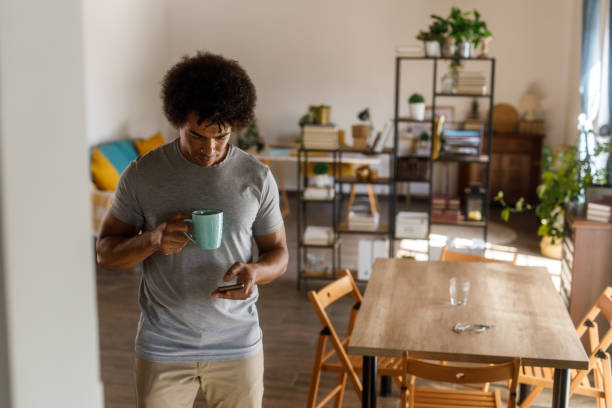 istock Man walking through his home, using smart phone and enjoying coffee 1960403233