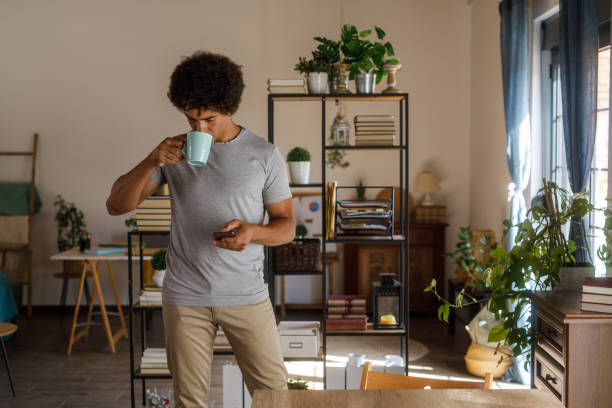 istock Man walking through his home, using smart phone and enjoying coffee 1960403234