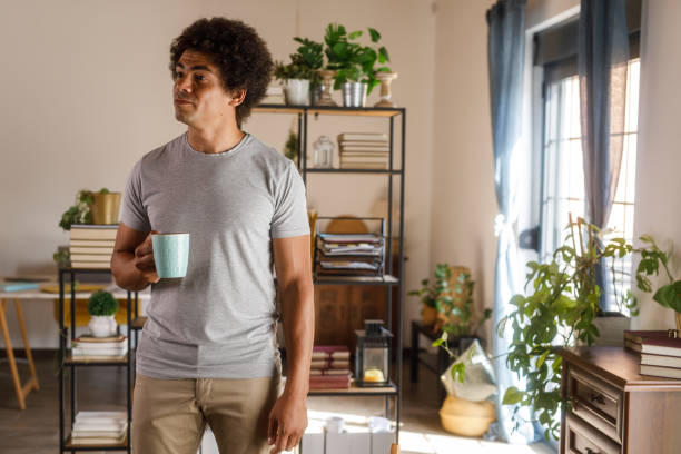 istock Man walking around his home, carrying a cup of coffee 1960404836