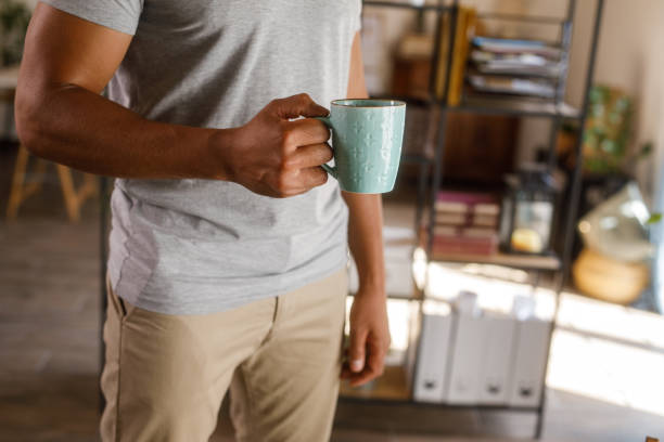 istock Man walking around his home, carrying a cup of coffee 1960405877