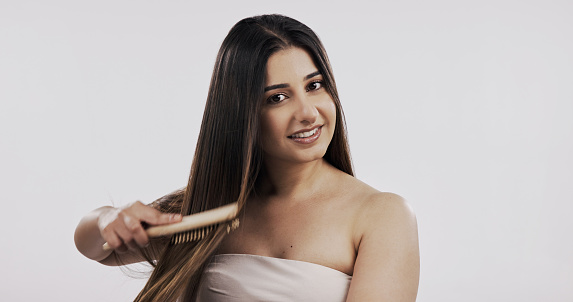 Beauty, portrait and happy woman brushing hair in studio shampoo, results or wellness on white background. Haircare, face and comb by Indian female model with volume, growth or texture satisfaction