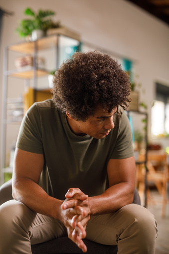 Portrait of worried mid adult man battling a bad mental health day, struggling with anxiety, fidgeting his hands and cracking his knuckles nervously.