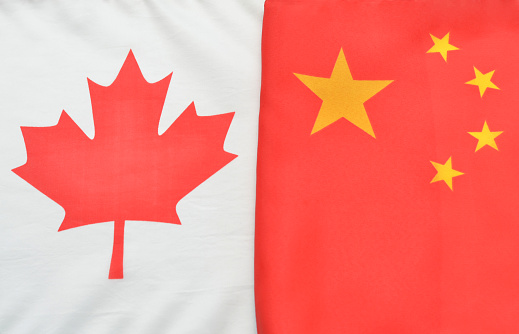 Closeup of a Canadian Flag and a Chinese Flag side by side symbolizing Canadian and Chinese relationships.