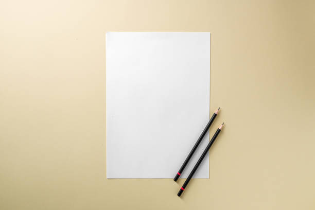 istock Blank white paper and black pencil on yellow background 1960417476