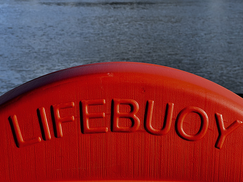 Red lifebuoy positioned by the beach, and ready to be used in an emergency