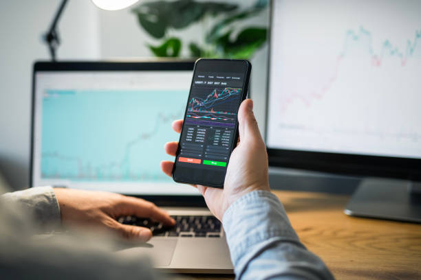 istock Man looking at currency trading app on his smart phone from his home office. 1960426985