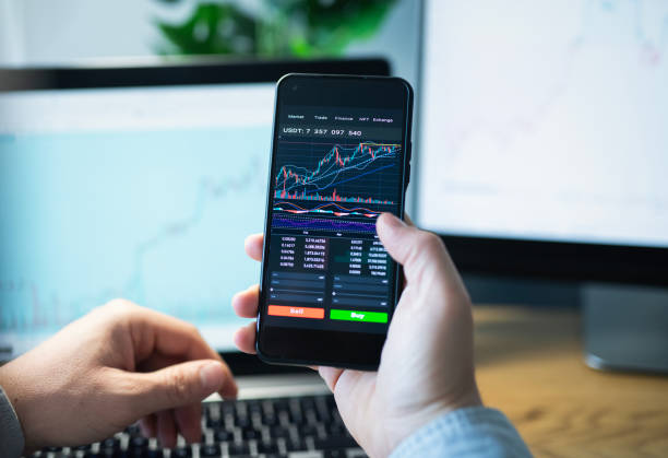 istock Man looking at currency trading app on his smart phone from his home office. 1960427014