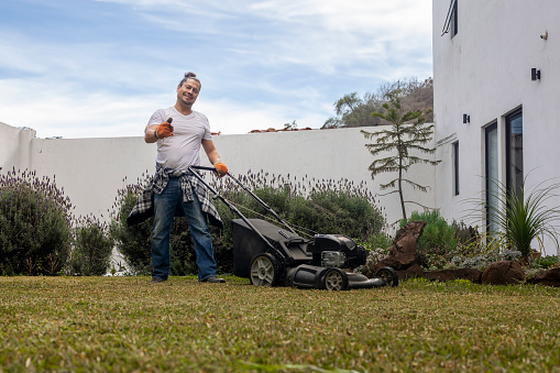 Gardener working with a lawn mower during a work hard day