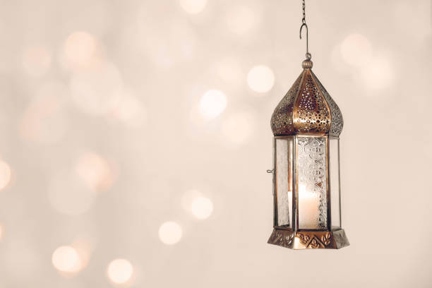 istock Hanging copper burning Moroccan lantern. Festive pale beige background with glittering bokeh lights. Ramadan Kareem muslim holiday still life. Neutral blurred background. Elegant Iftar dinner. 1960431311