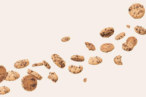 Chocolate cookies flying on a cream background. Biscuit sweet food concept.