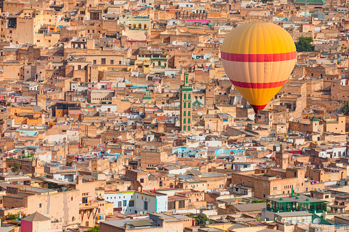 Hot air balloon flying over many buildings within the Medina of Fes, Morocco