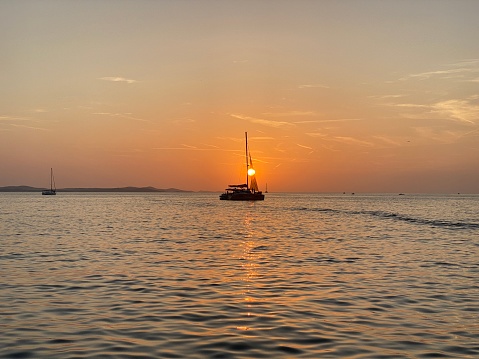sea ​​landscape at sunset with a sailboat in front of the sun. horizon over the water. cloudless orange sky. Mediterranean Sea